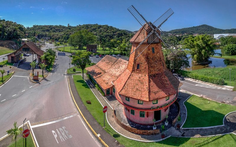 Vista aérea do Moinho da XV, réplica de moinho holandês, à beira de uma avenida arborizada em Joinville.