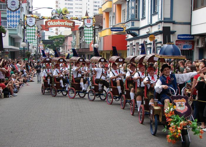 Grupo de pessoas em trajes típicos dançando em festa cultural com bandeirinhas coloridas.