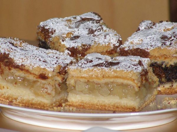 Pedaço de cuca com farofa doce por cima, sobre prato de cerâmica.