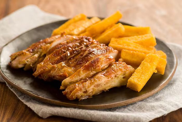 Prato com pedaços de galeto assado e bastões de polenta frita.